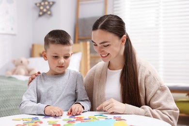 Photo of Dyslexia. Mother and her son learning letters at table indoors