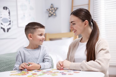 Photo of Dyslexia. Mother and her son learning letters at table indoors