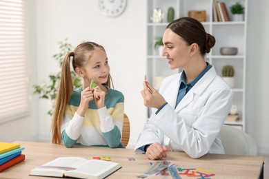 Photo of Dyslexia treatment. Pediatrician working with little girl at table indoors