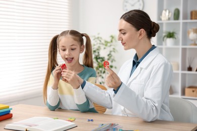 Photo of Dyslexia treatment. Pediatrician working with little girl at table indoors