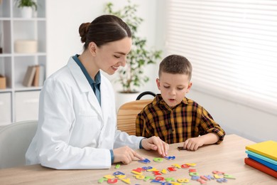 Photo of Dyslexia treatment. Pediatrician working with little boy at table indoors