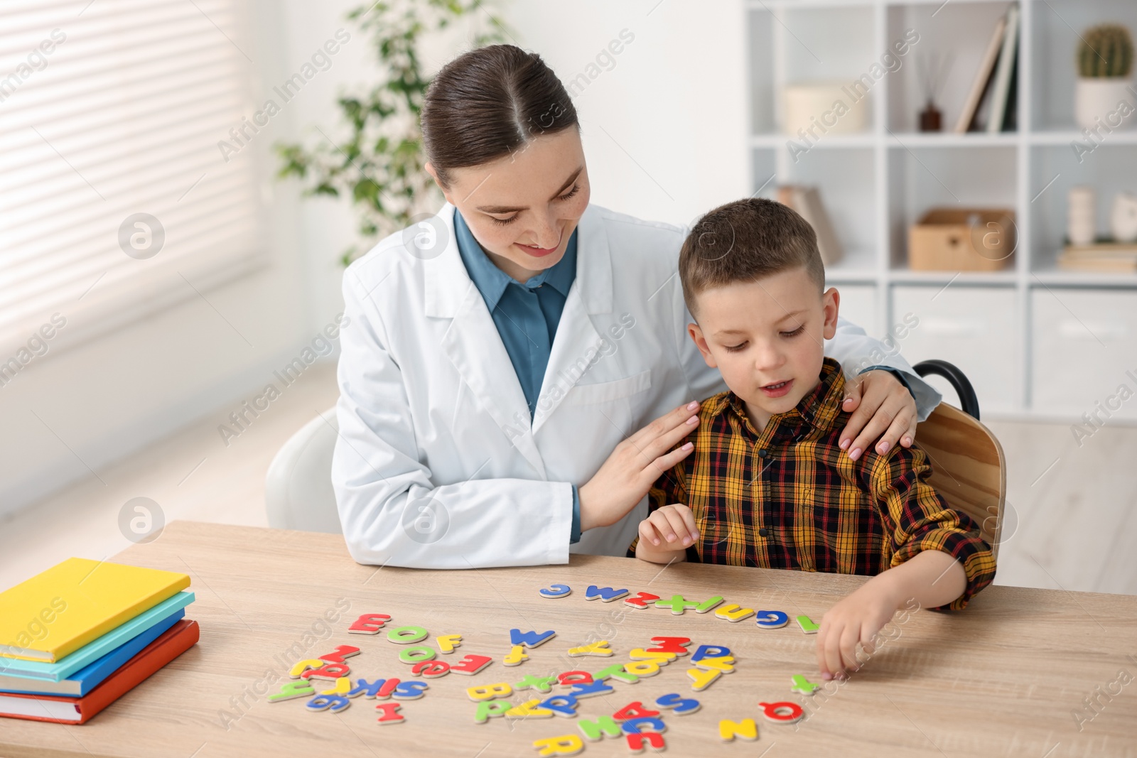 Dyslexia treatment. Pediatrician working with little boy at table indoors Photo of Dyslexia treatment. Pediatrician working with little boy at table indoors