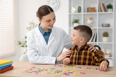 Photo of Dyslexia treatment. Pediatrician working with little boy at table indoors