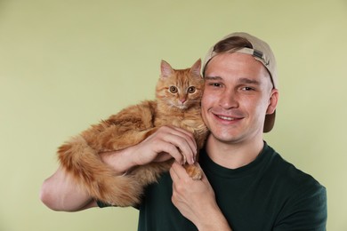 Photo of Man with cute ginger cat on light green background