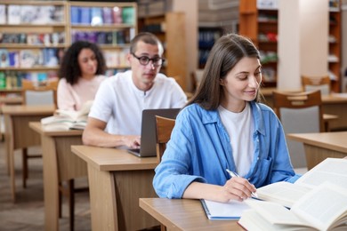 Photo of People studying at desks in public library, selective focus