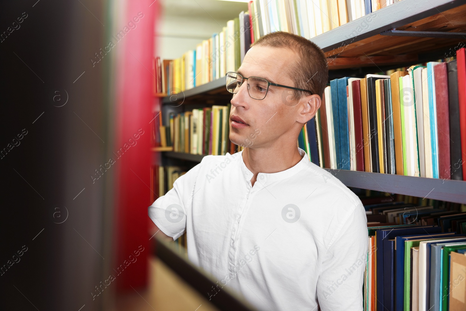 Photo of Man choosing book from shelf in public library