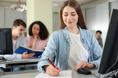 Photo of People working at desks in library, selective focus