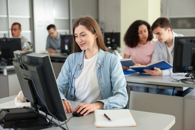 Photo of People working at desks in library, selective focus