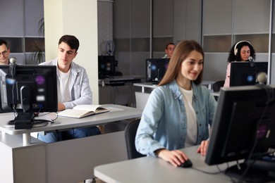 Photo of People working at desks in library, selective focus