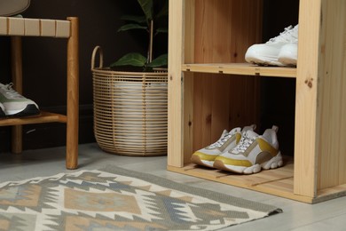 Photo of Different footwear on shelves in entryway, closeup. Shoe storage
