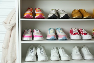 Photo of Different footwear on shelves indoors, closeup. Shoe storage