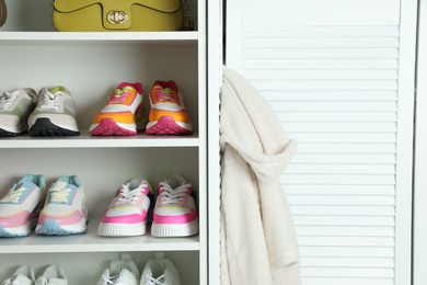 Photo of Different footwear on shelves indoors, closeup. Shoe storage
