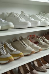 Photo of Different footwear on shelves indoors, closeup. Shoe storage