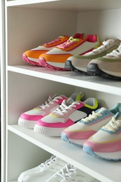 Photo of Different footwear on shelves indoors, closeup. Shoe storage