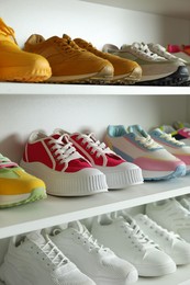 Photo of Different footwear on shelves indoors, closeup. Shoe storage