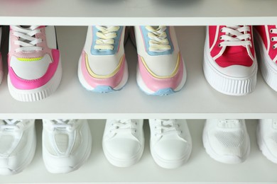 Photo of Different footwear on shelves indoors, closeup. Shoe storage
