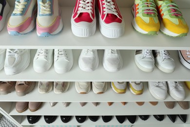 Photo of Different footwear on shelves indoors, closeup. Shoe storage