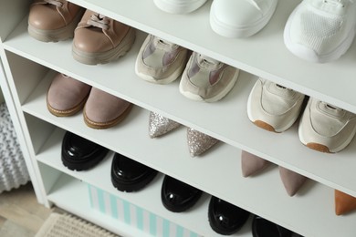 Photo of Different footwear on shelves indoors, closeup. Shoe storage