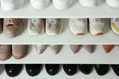 Photo of Different footwear on shelves indoors, closeup. Shoe storage