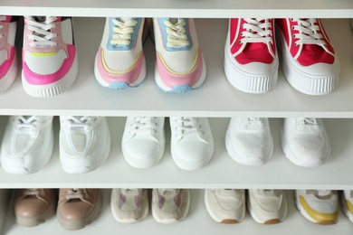 Photo of Different footwear on shelves indoors, closeup. Shoe storage