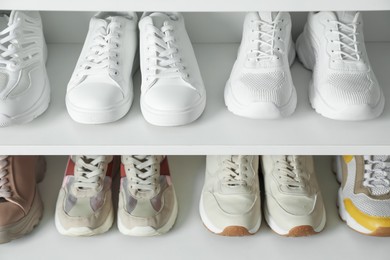 Photo of Different footwear on shelves indoors, closeup. Shoe storage