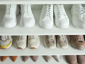 Photo of Different footwear on shelves indoors, closeup. Shoe storage