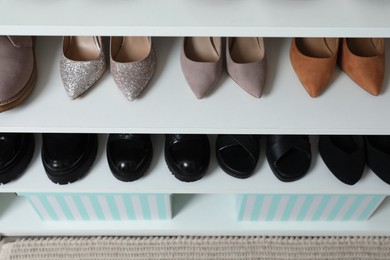 Photo of Different footwear on shelves indoors, closeup. Shoe storage