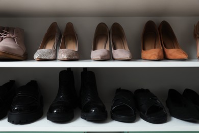 Photo of Different footwear on shelves indoors, closeup. Shoe storage