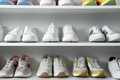 Photo of Different footwear on shelves indoors, closeup. Shoe storage