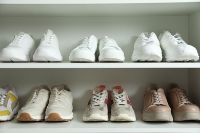 Photo of Different footwear on shelves indoors, closeup. Shoe storage