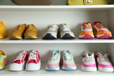 Photo of Different footwear on shelves indoors, closeup. Shoe storage