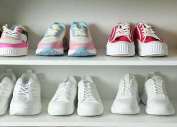 Photo of Different footwear on shelves indoors, closeup. Shoe storage