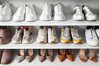 Photo of Different footwear on shelves indoors, closeup. Shoe storage