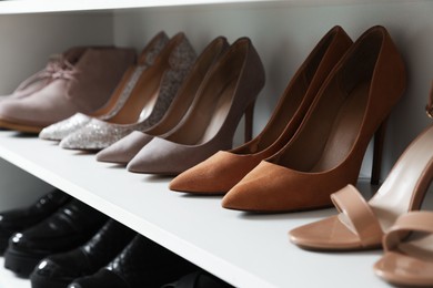 Photo of Different footwear on shelves indoors, closeup. Shoe storage