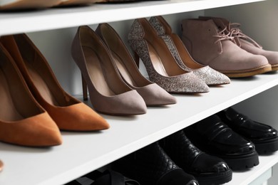 Photo of Different footwear on shelves indoors, closeup. Shoe storage