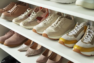 Photo of Different footwear on shelves indoors, closeup. Shoe storage