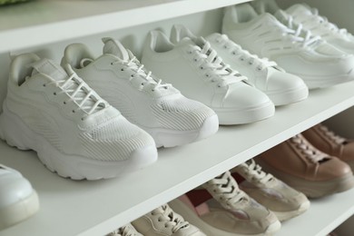 Photo of Different footwear on shelves indoors, closeup. Shoe storage