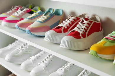 Photo of Different footwear on shelves indoors, closeup. Shoe storage