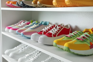 Photo of Different footwear on shelves indoors, closeup. Shoe storage