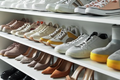 Photo of Different footwear on shelves indoors, closeup. Shoe storage