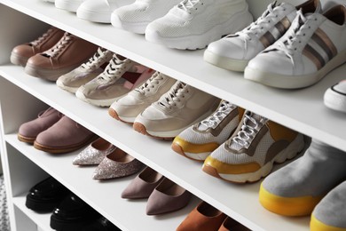 Photo of Different footwear on shelves indoors, closeup. Shoe storage