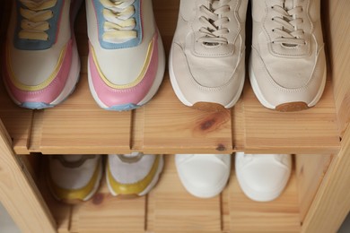 Photo of Different footwear on shelves indoors, closeup. Shoe storage