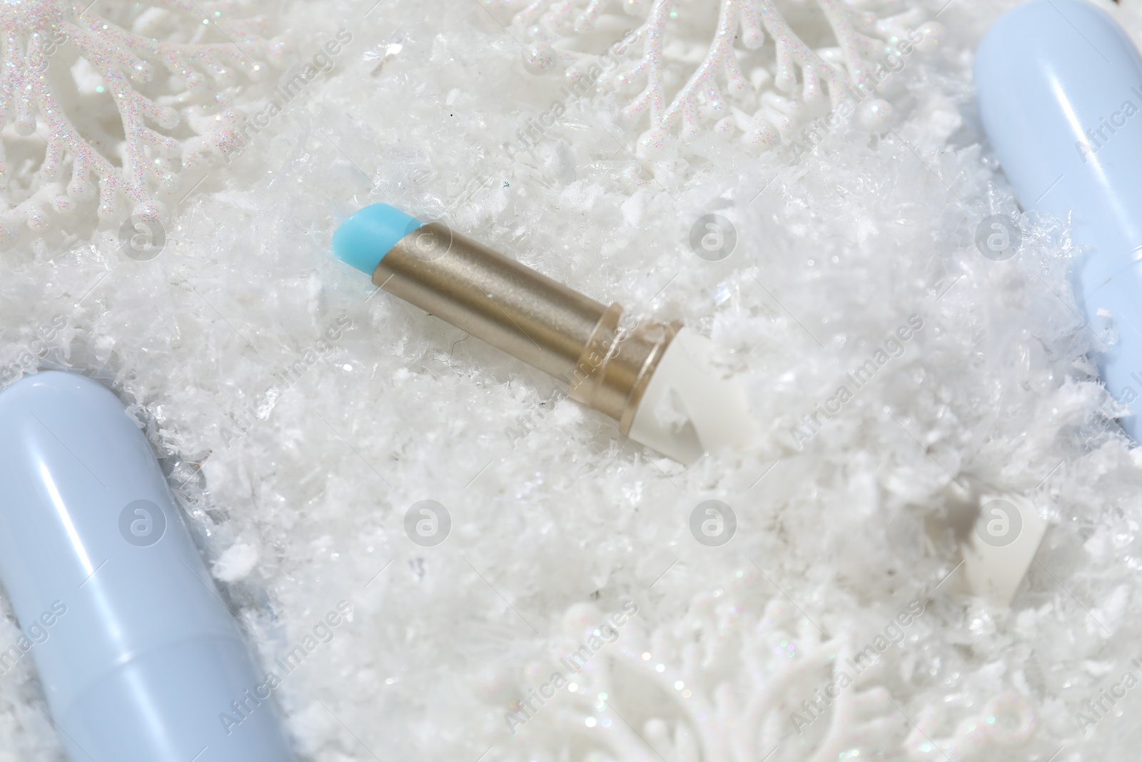 Moisturizing lip balms and Christmas decor on artificial snow, closeup. Winter care Photo of Moisturizing lip balms and Christmas decor on artificial snow, closeup. Winter care