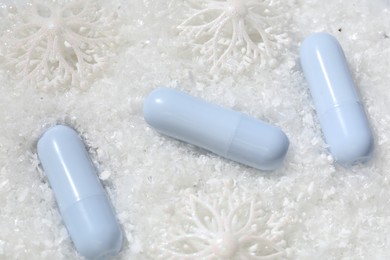 Photo of Moisturizing lip balms and Christmas decor on artificial snow, flat lay. Winter care