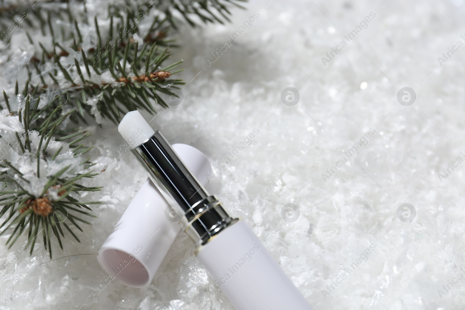 Moisturizing lip balm and fir tree branches on artificial snow, closeup. Space for text Photo of Moisturizing lip balm and fir tree branches on artificial snow, closeup. Space for text