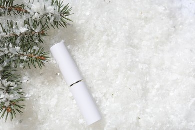 Photo of Moisturizing lip balm and fir tree branches on artificial snow, flat lay. Space for text
