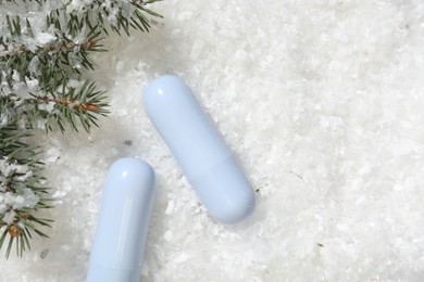 Photo of Moisturizing lip balms and fir tree branches on artificial snow, flat lay. Space for text