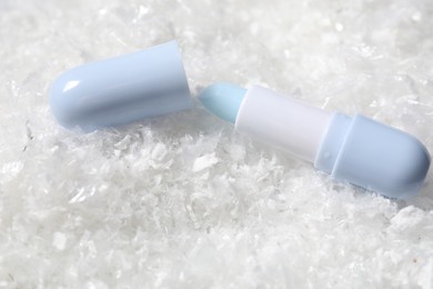 Photo of Moisturizing lip balm on artificial snow, closeup. Winter care