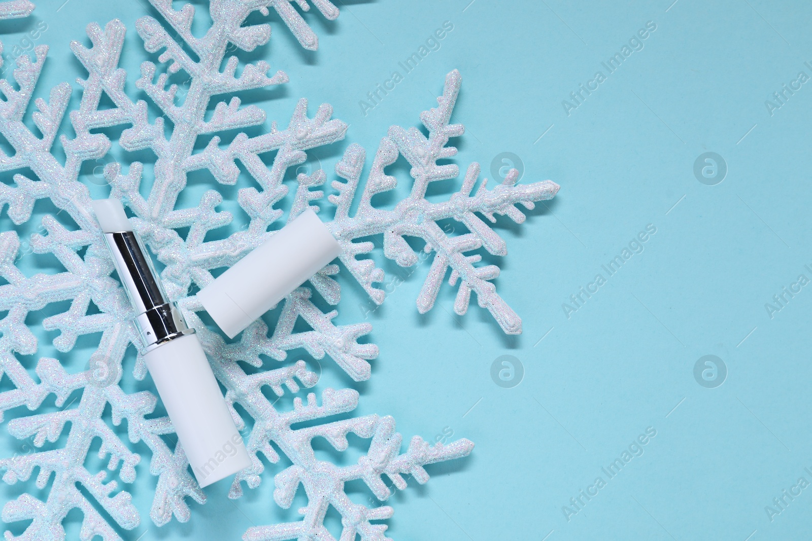 Moisturizing lip balm and Christmas decor on light blue background, flat lay. Space for text Photo of Moisturizing lip balm and Christmas decor on light blue background, flat lay. Space for text