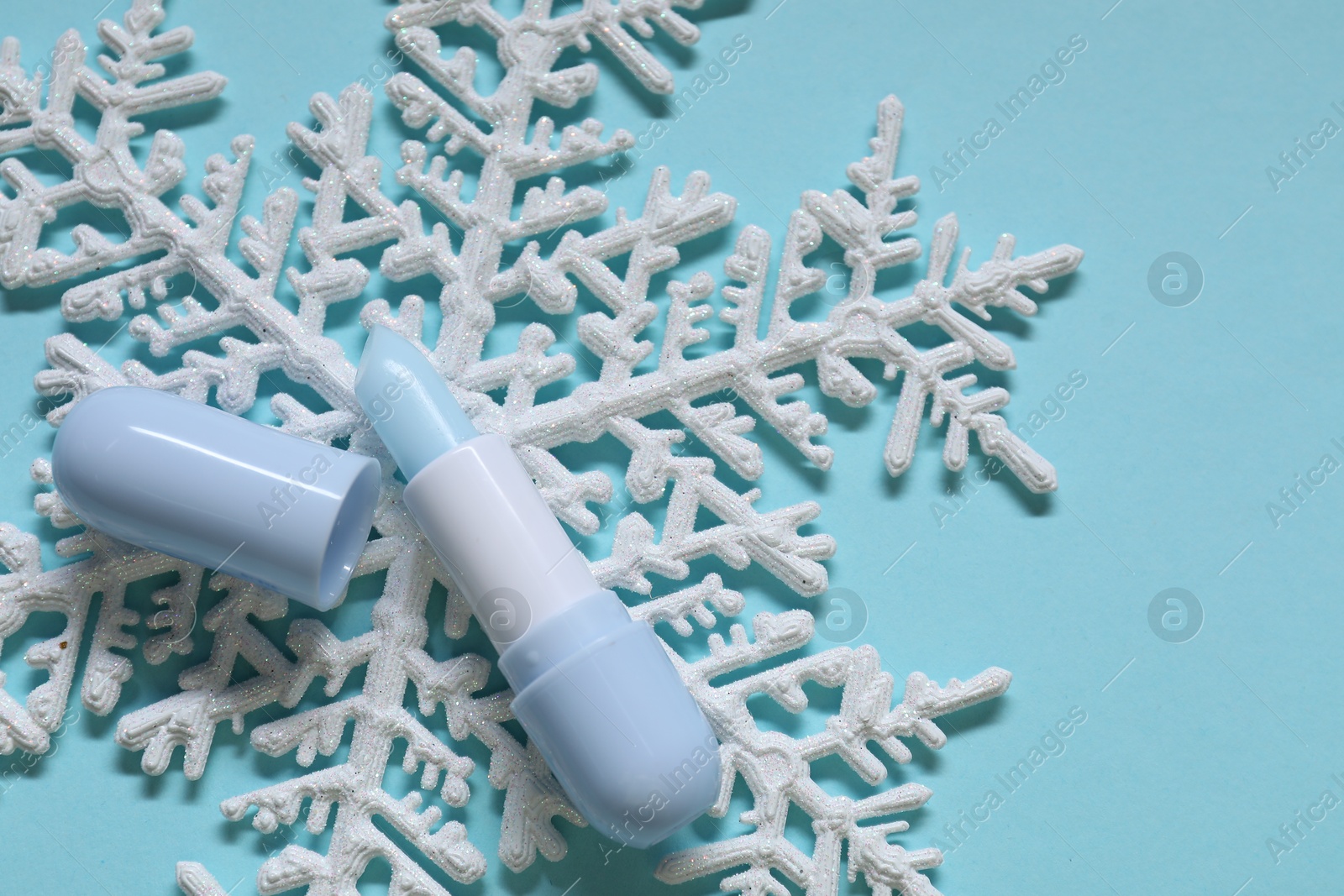 Moisturizing lip balm and Christmas decor on light blue background, flat lay. Winter care Photo of Moisturizing lip balm and Christmas decor on light blue background, flat lay. Winter care